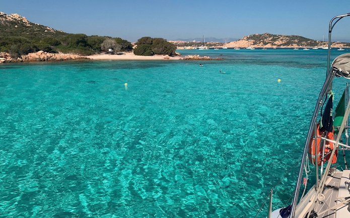 Catamaran sailing near La Maddalena with clear turquoise waters and distant islands.
