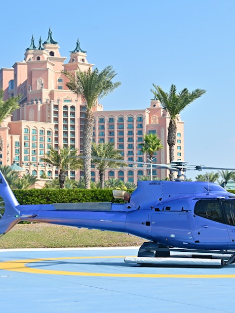 Helicopter on helipad with Atlantis The Palm hotel in Dubai background.