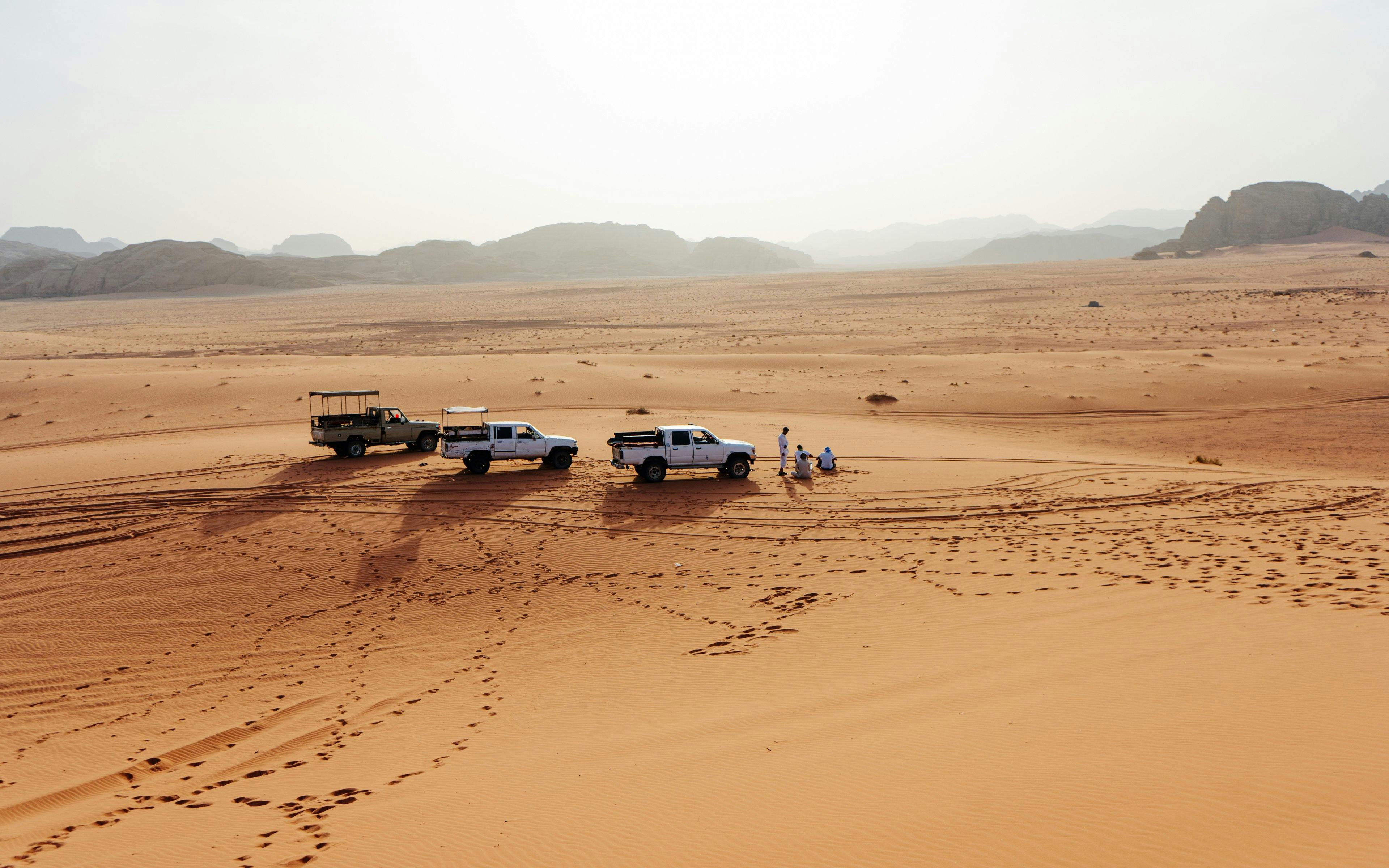 4x4 vehicles on Wadi Rum desert tour with distant mountains in Jordan.