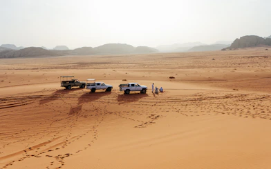 4x4 vehicles on Wadi Rum desert tour with distant mountains in Jordan.