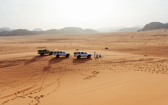 4x4 vehicles on Wadi Rum desert tour with distant mountains in Jordan.