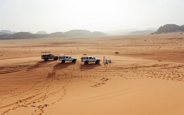 4x4 vehicles on Wadi Rum desert tour with distant mountains in Jordan.