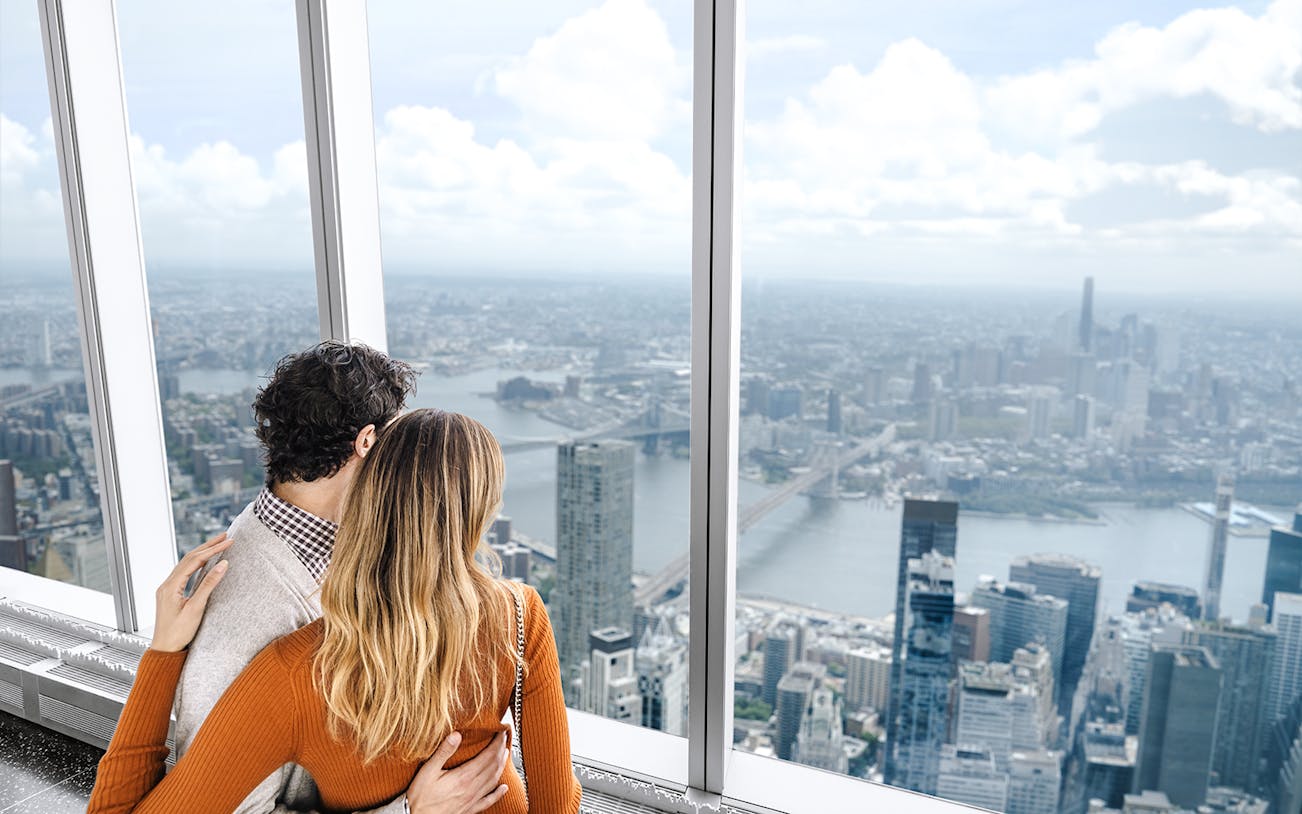 Couple enjoying New York City skyline view from One World Observatory.