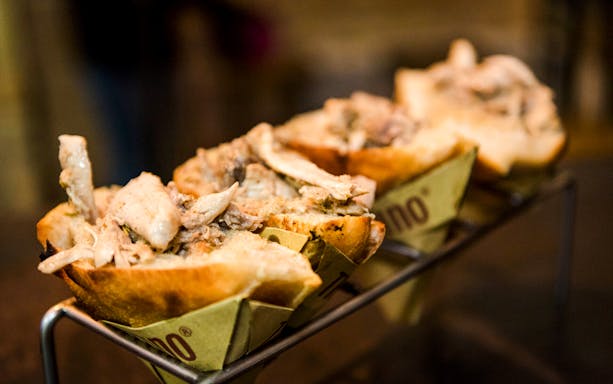 Trapizzino filled with chicken on a serving rack in Rome, Italy.