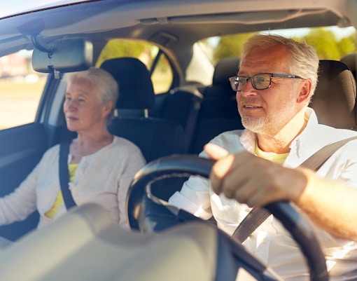 Senior couple driving in a car on a sunny day.