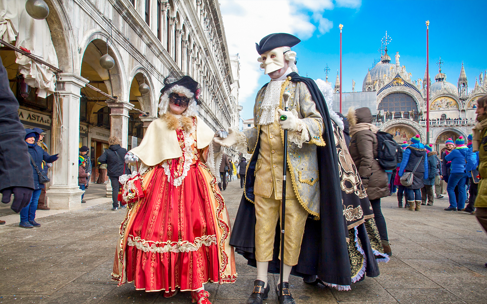 Venice Carnival participants in traditional masks and costumes in St. Mark's Square, Venice, Italy.