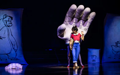 Performer on stage with large hand prop during Drawn to Life show.