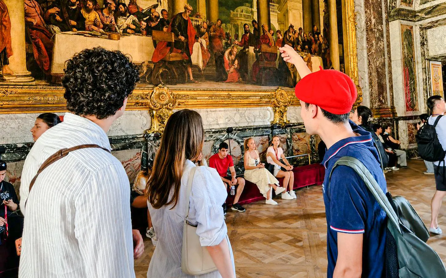 Visitors admire artwork during a guided tour inside Versailles Palace.