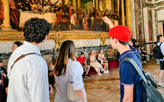 Visitors admire artwork during a guided tour inside Versailles Palace.