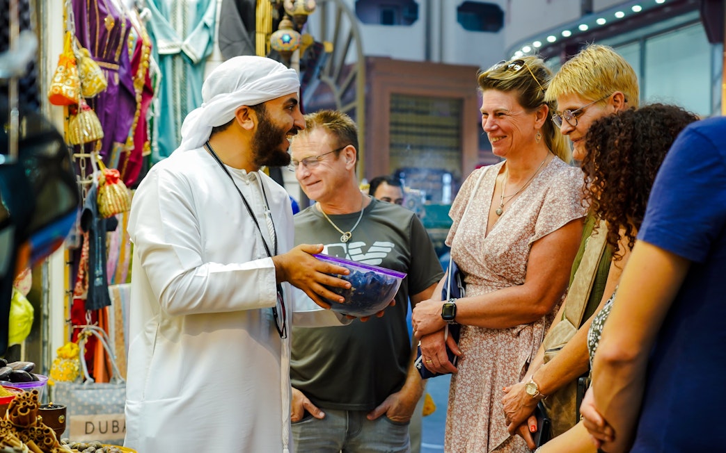 Guide engaging with tourists in a vibrant Dubai market.