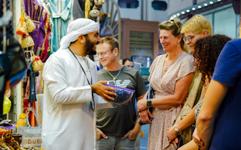 Guide engaging with tourists in a vibrant Dubai market.