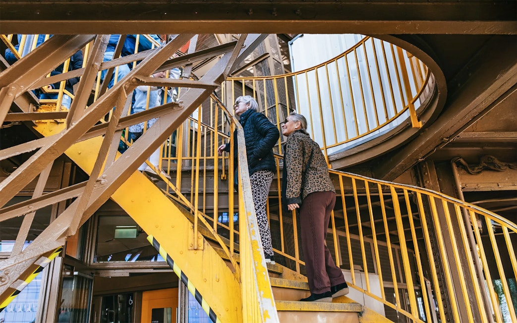 Visitors ascending Eiffel Tower stairs during guided tour in Paris.