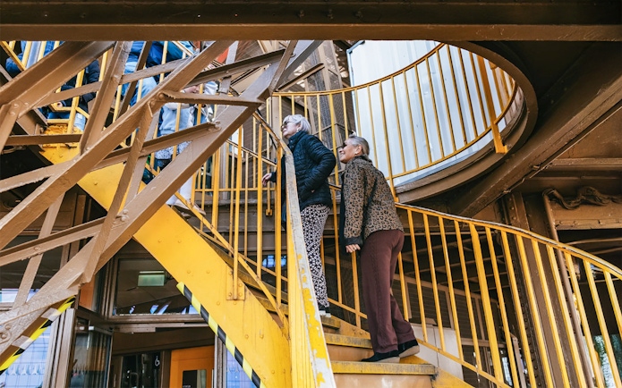 Visitors ascending Eiffel Tower stairs during guided tour in Paris.