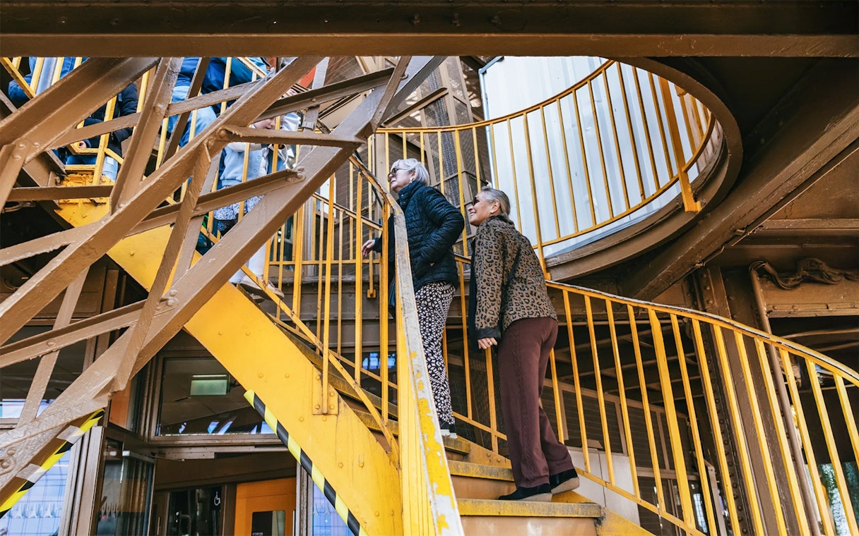 Visitors ascending Eiffel Tower stairs during guided tour in Paris.