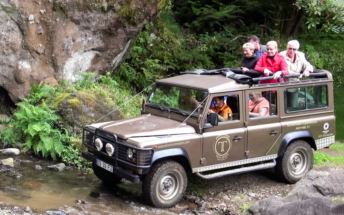 Jeep tour through Madeira forest with passengers enjoying the scenic view.