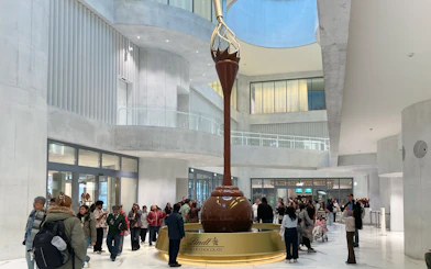 Visitors inside Lindt Home of Chocolate Museum Zurich, viewing large chocolate fountain.