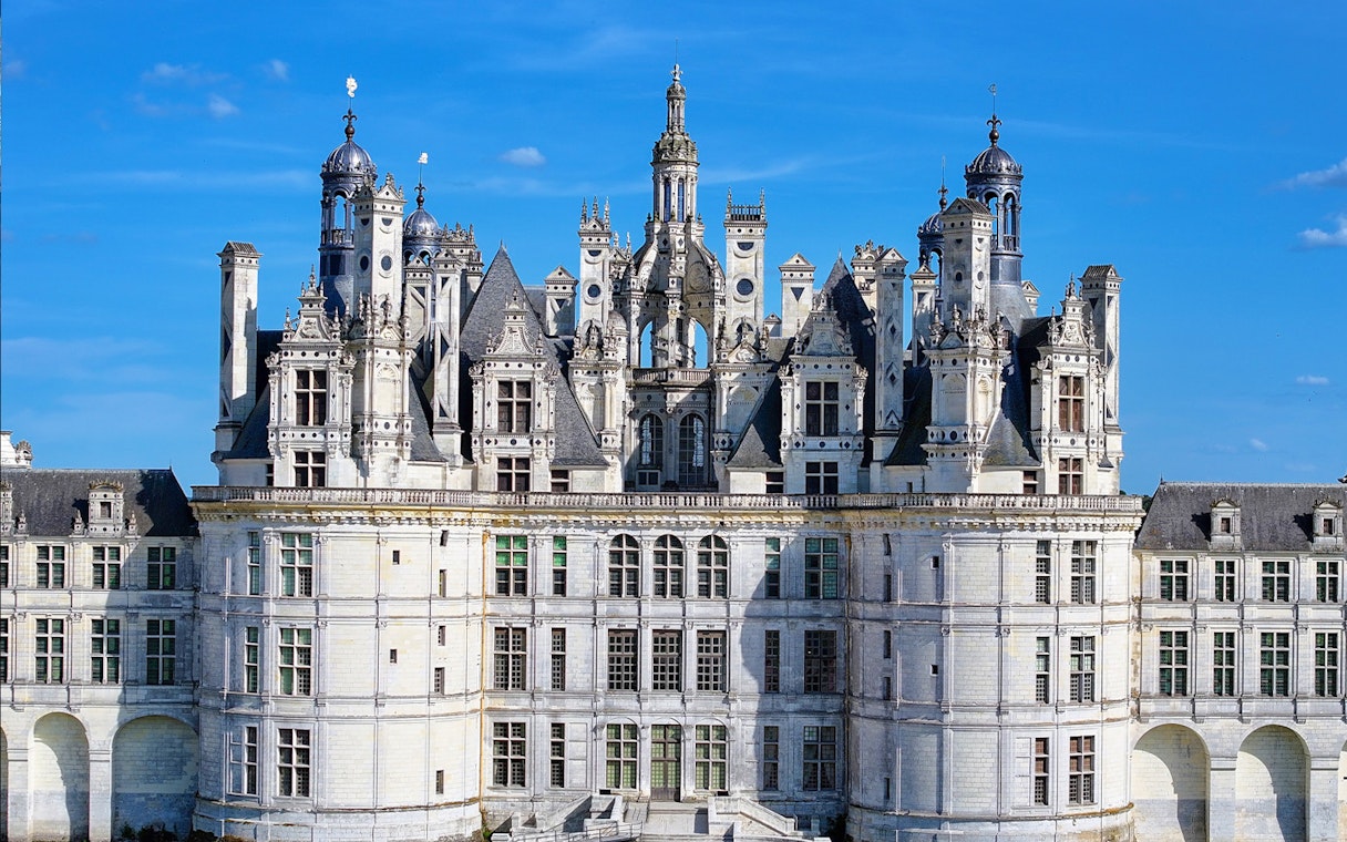 Château de Chambord facade with intricate towers and spires under a clear blue sky.