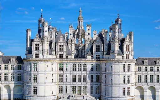 Château de Chambord facade with intricate towers and spires under a clear blue sky.