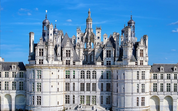 Château de Chambord facade with intricate towers and spires under a clear blue sky.