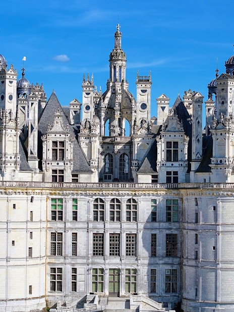 Château de Chambord facade with intricate towers and spires under a clear blue sky.