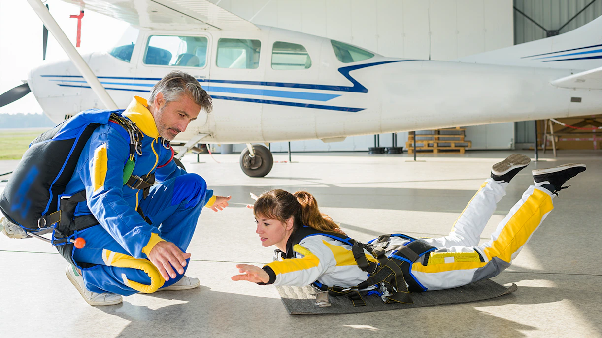 Skydiving instructor guiding a trainee in a hangar near a plane in Sydney.