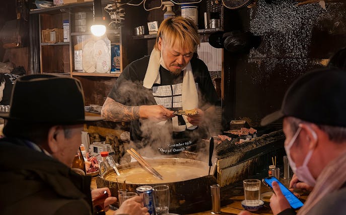 Chef preparing food at a bar during the Shinjuku Local Bar & Izakaya Crawl Tour in Tokyo.