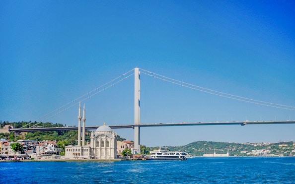 Bosphorus Bridge view during Golden Horn Cruise with mosque and ferry in Istanbul.