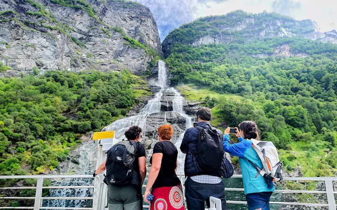Tourists on a boat admire a waterfall in Geiranger Fjord, Norway.