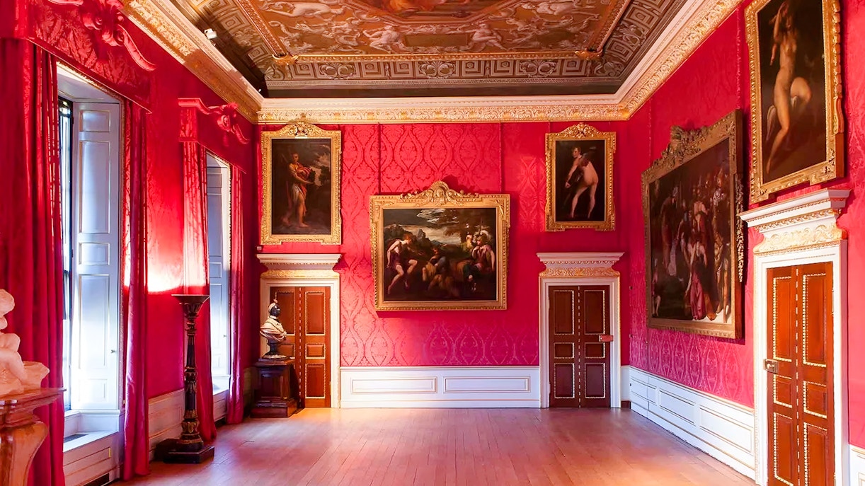 Kensington Palace interior with ornate paintings and red walls.