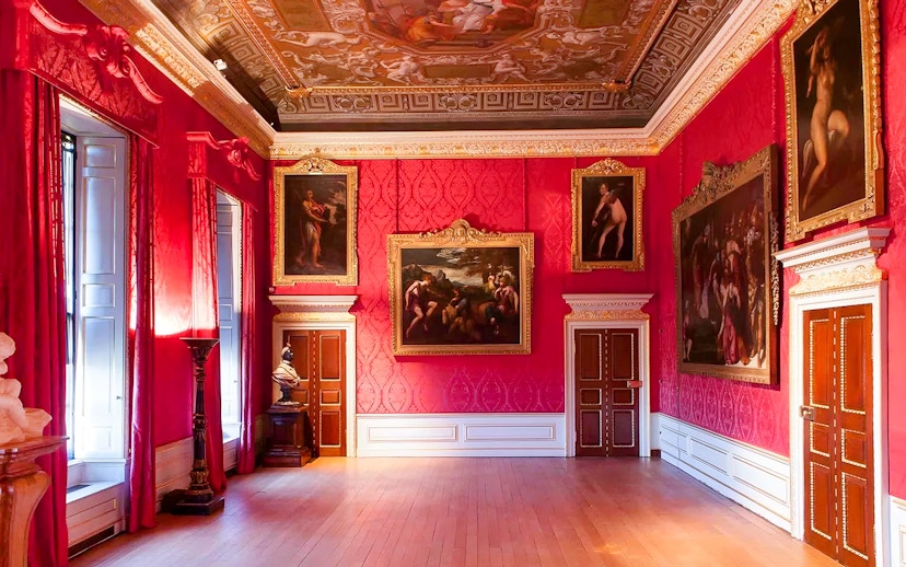 Kensington Palace interior with ornate paintings and red walls.