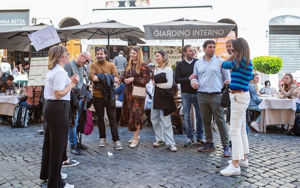 Group on a guided street food tour in Campo de' Fiori, Rome, near outdoor cafes.