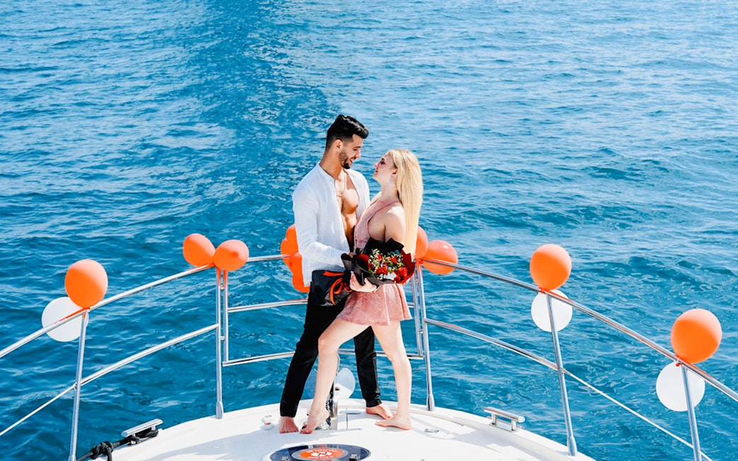 Couple embracing on a private yacht decorated with balloons, Dubai.