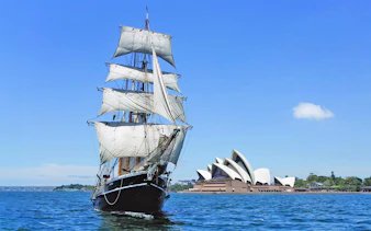 Tall ship sailing in Sydney Harbour with Sydney Opera House in the background.