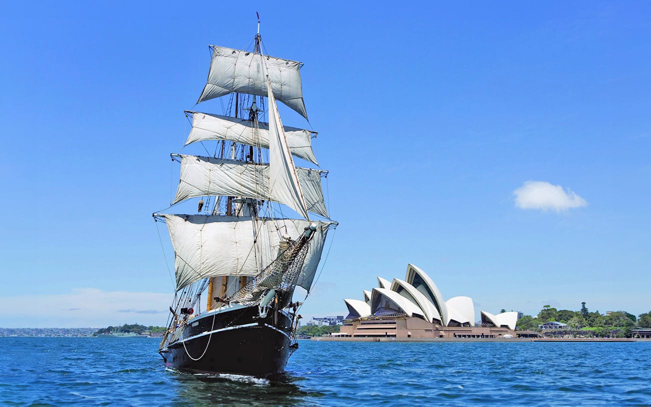 Tall ship sailing in Sydney Harbour with Sydney Opera House in the background.