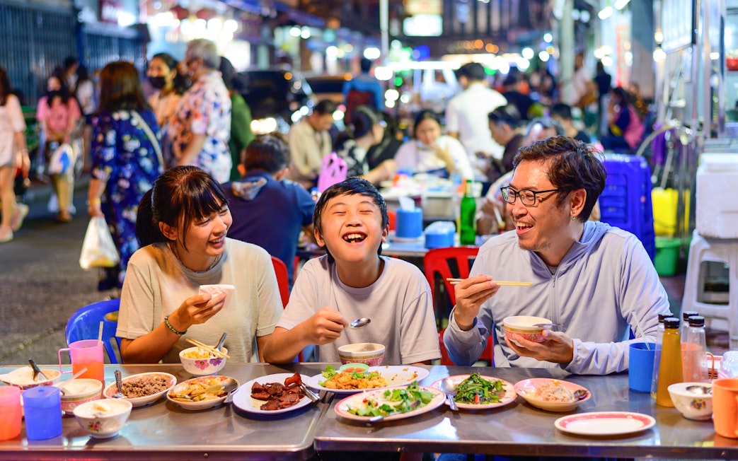 Family dining at a street food stall in Bangkok's Chinatown during a guided tuk-tuk tour.