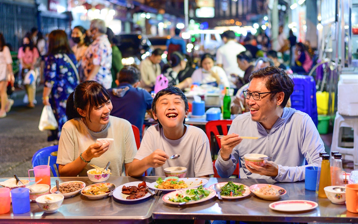 Family dining at a street food stall in Bangkok's Chinatown during a guided tuk-tuk tour.