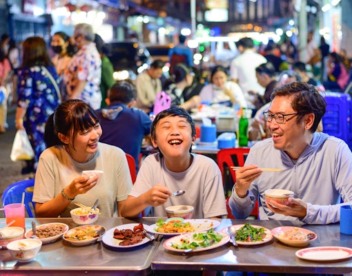 Family dining at a street food stall in Bangkok's Chinatown during a guided tuk-tuk tour.