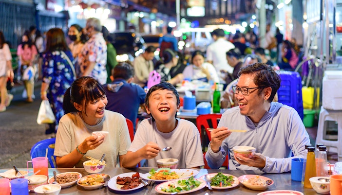 Family dining at a street food stall in Bangkok's Chinatown during a guided tuk-tuk tour.