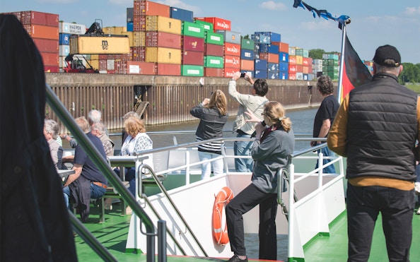 Tourists on a boat viewing shipping containers at Cologne Harbour.