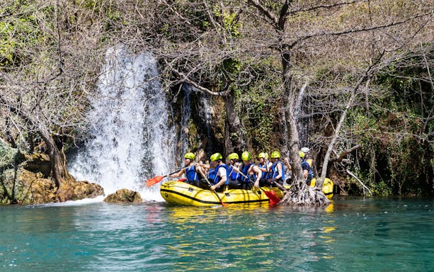 Rafting group navigating Cetina River near a waterfall in Croatia.