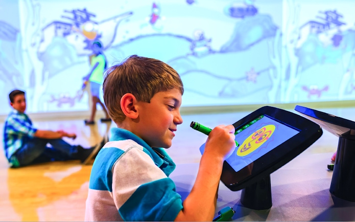 Child drawing on digital screen at Crayola Experience in Orlando.