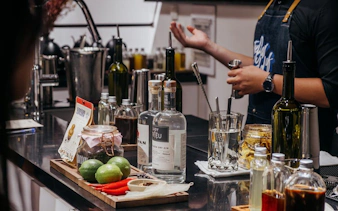 Bartender preparing coffee-themed cocktails with limes and spices in a Vietnamese bar setting.