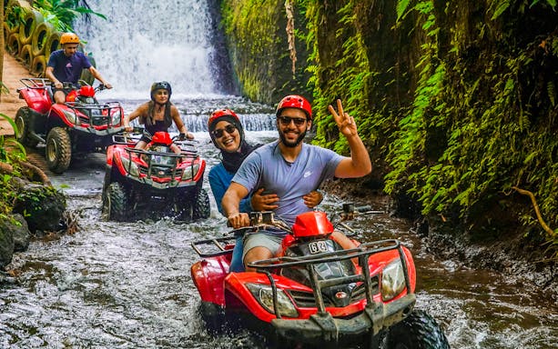 ATV riders navigating a jungle stream near Goa Raja Waterfall in Ubud.