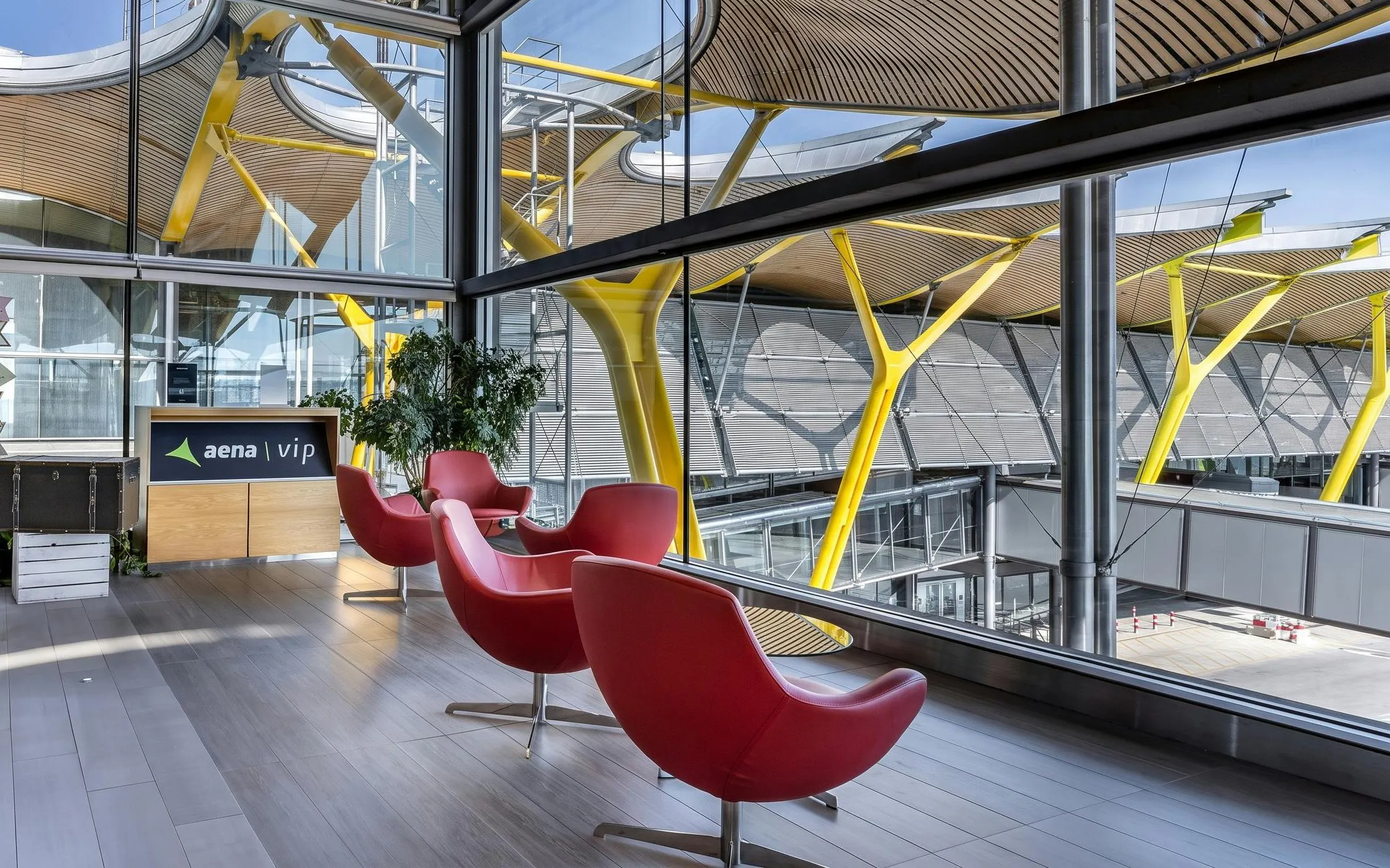 Sala VIP Neptuno lounge with red chairs and large windows at Adolfo Suarez-Barajas Airport, Madrid.