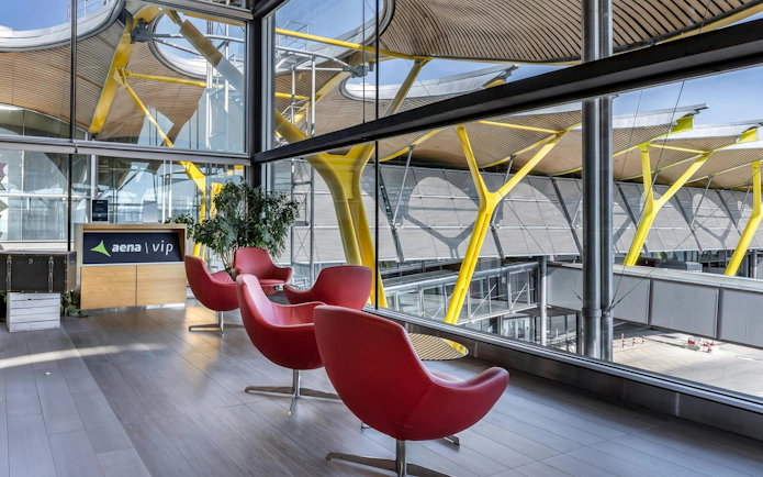 Sala VIP Neptuno lounge with red chairs and large windows at Adolfo Suarez-Barajas Airport, Madrid.