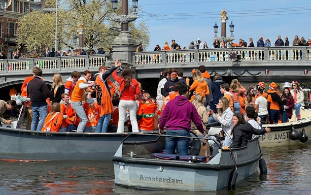 People celebrating on boats during Kingsday in Amsterdam.