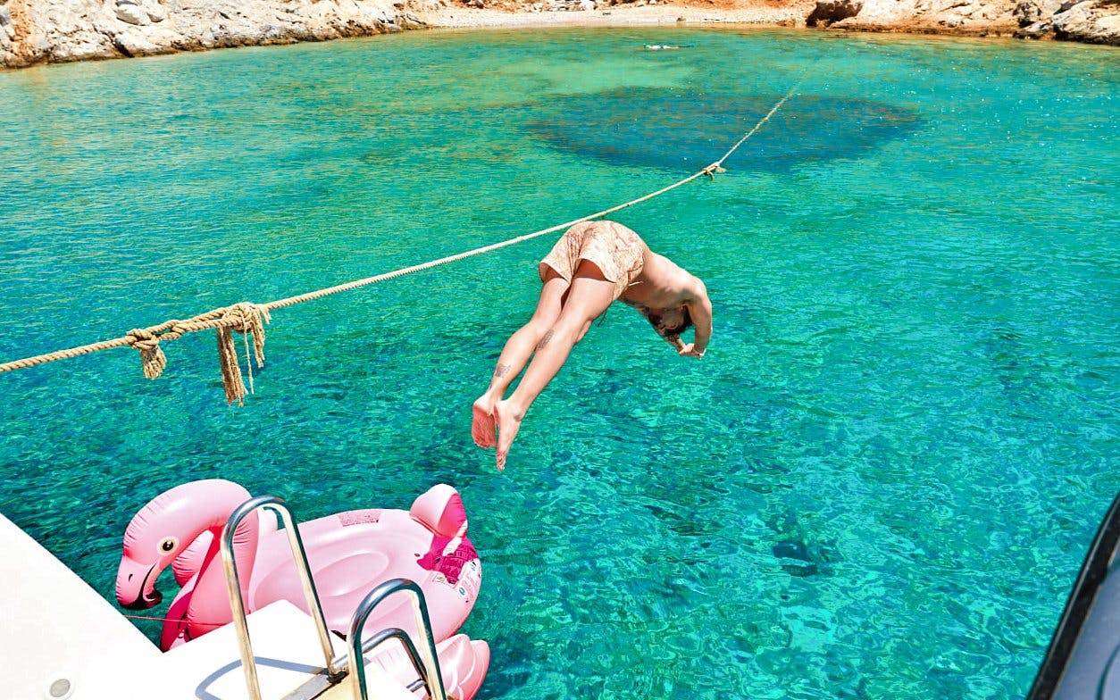 Diver jumping into clear water from a catamaran near Dia Island.
