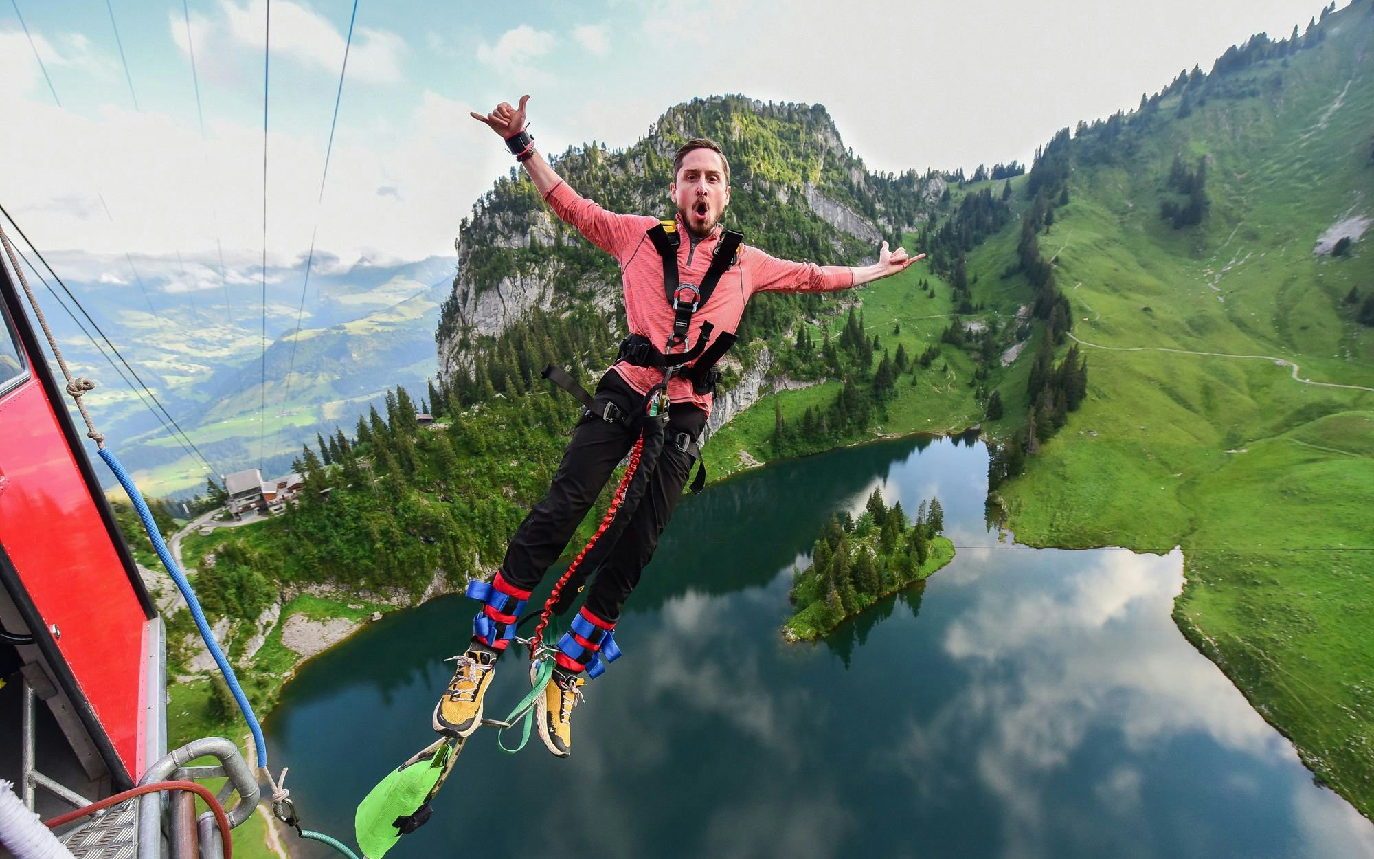 Bungee jumper mid-air over Stockhorn Interlaken with lake and mountains in view.