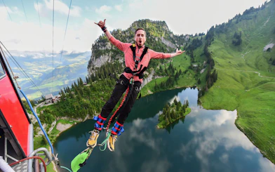 Bungee jumper mid-air over Stockhorn Interlaken with lake and mountains in view.