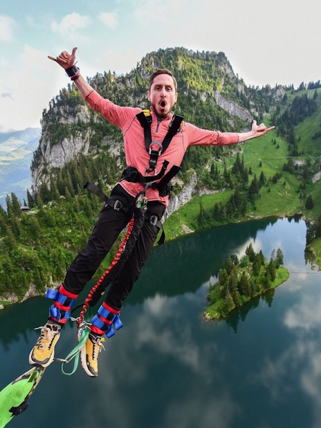 Bungee jumper mid-air over Stockhorn Interlaken with lake and mountains in view.